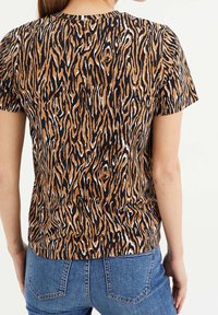 Brun och svart kortärmad topp med ett vågigt djurmönster i ett lätt material, med rund halsringning och avslappnad passform.