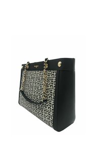 Tote bag a fantasia bianco e nero con un design geometrico, dotata di manici a catena dorati, dettagli metallici e una forma strutturata.