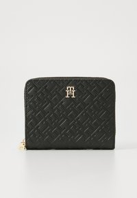 Portefeuille en cuir noir avec un motif géométrique en relief, matériel doré et fermeture à glissière. Présente un logo à l'avant et une surface texturée.