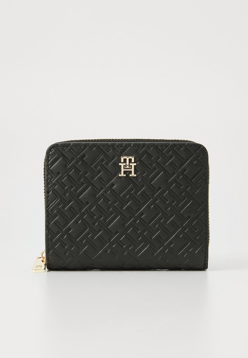 Portefeuille en cuir noir avec un motif géométrique en relief, matériel doré et fermeture à glissière. Présente un logo à l'avant et une surface texturée.