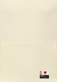 Sweat-shirt couleur crème avec une poche avant, une texture douce et une étiquette portant l'inscription "ONLY VINTAGE" accompagnée d'un logo cœur et planète.