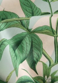 Stof met grote, gedetailleerde groene bladeren, met fijne lijnen en een zachte textuur; de achtergrond heeft een gedempt lichte kleur met bloemaccenten.