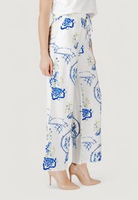 Pantaloni bianchi a gamba larga con motivo floreale blu e accenti verdi. Materiale leggero, vita elastica e chiusura con cordoncino.