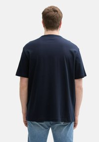 Granatowa bawełniana koszulka z krótkim rękawem i okrągłym dekoltem, z gładkim plecakiem i luźnym krojem. Brak widocznych logo lub wzorów.