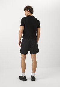 Camiseta atlética negra y pantalones cortos, fabricados con material liviano, diseño ajustado. Cuenta con mangas cortas y cintura elástica. Estilo minimalista, sin patrones.