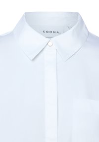Weißes Hemd mit versteckter Knopfleiste und einer einzelnen Brusttasche, gekennzeichnet mit dem Markenlabel "COMMA" innen am Kragen.