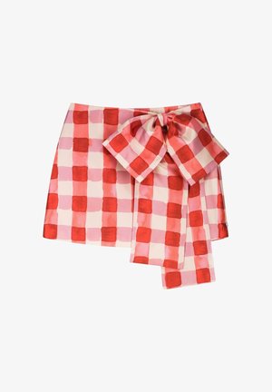 Roter und pink karierter Minirock mit großer passender Schleife, die an der Taille auf einem schlichten weißen Hintergrund gebunden ist.