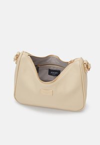 Sac à épaule en cuir beige avec fermeture éclair dorée ouverte, montrant un intérieur gris clair et une poche zippée avec l'étiquette JOOP! Jeans à l'intérieur.