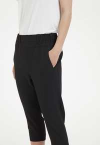 Pantalones cortos negros con cinturilla elástica y bolsillos laterales, que presentan un diseño liso y ajustado, además de un material ligero.