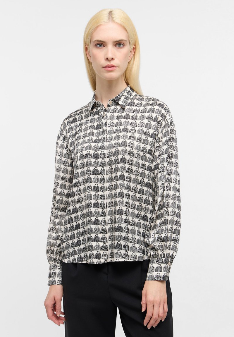 Chemise à manches longues à boutons en crème avec impression graphique noire. Dotée d'un col et de poignets, en tissu léger et lisse avec une coupe décontractée.