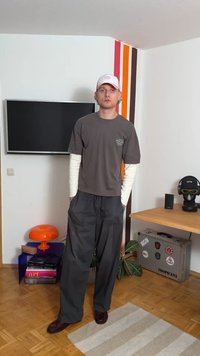 Pelēks T-krekls, kas uzvilkts virs baltām garām piedurknēm, apvienots ar brīvi pieguļošām pelēkām biksēm. Aksesuāri ietver rozā cepuri un bordo apavus.