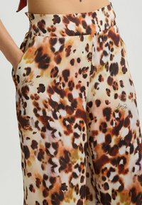 Luipaardprint broek van lichtgewicht, gladde stof in beige met bruine en zwarte vlekken. Inclusief zijzakken en een ontwerperslogo.