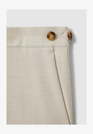 Pantaloni in tessuto beige con finitura testurizzata, caratterizzati da due bottoni marroni in vita e un dettaglio di piega sottile.