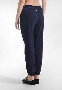 Tmavě modré volnočasové kalhoty s elastickým pasem, zúženými manžetami a měkkou tkaninou. Na zadním pásku je malá logo štítek.