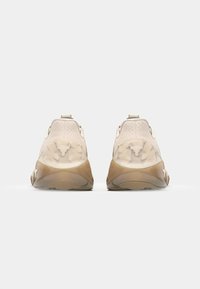 Scarpe da ginnastica beige con tacco testurizzato, tomaia liscia e dettagli traslucidi, dotate di suola in gomma. La vista posteriore mette in evidenza gli elementi del design.