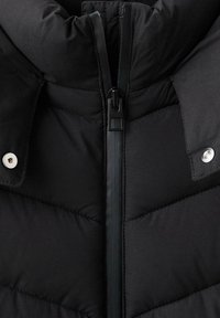 Czarna puchowa kurtka z wysokim kołnierzem, diagonalną pikowaną fakturą, asymetrycznym zamkiem błyskawicznym i metalicznymi guzikami po bokach.