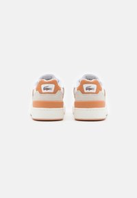 Baskets blanches avec des accents beiges et oranges, en matériaux en daim et cuir, avec un logo au niveau du talon. Bout rond et semelle plate.