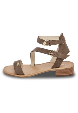 Sandale en daim marron avec plusieurs bandes, présentant des accents en métal doré et un petit talon en bois. Design à bout ouvert avec une semelle plate.