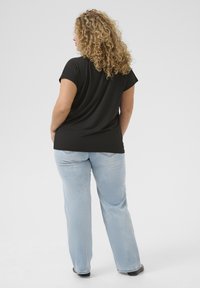 Svart T-shirt med korta ärmar, avslappnad passform, tillsammans med ljusblå raka jeans, bärs avslappnat. Slät textur, minimalistisk design.