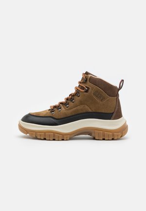 Brown suede and black synthetic mid-top hiking boot with textured rubber sole, brown laces, and contrasting beige midsole.