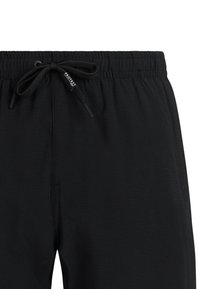 Pantalones cortos con cintura elástica negra y un cordón ajustable que presenta una pequeña etiqueta de la marca en uno de los extremos del cordón.