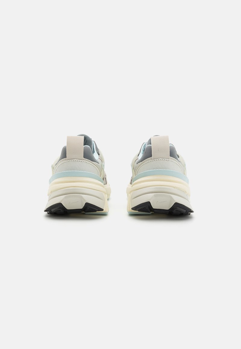 Vista trasera de unas zapatillas deportivas que presentan una combinación de colores gris claro y menta, materiales de malla y ante, una gruesa mediasuela color crema y suela de goma negra.
