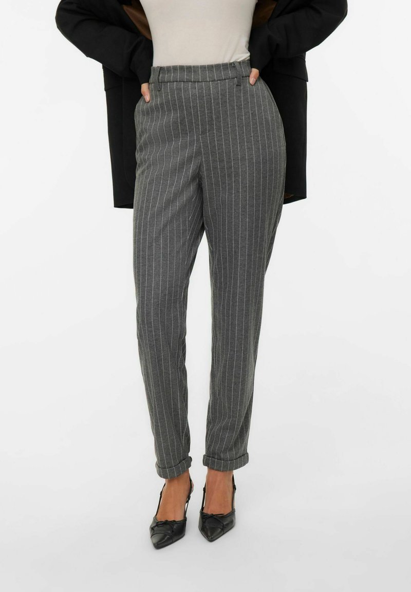 Szare spodnie w prążki o dopasowanym kroju, z wysokim stanem i podwiniętymi mankietami, zestawione z czarnymi szpilkami w szpic.