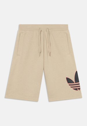 Šviesiai rudi šortai iš minkštos medžiagos, su juodu „Adidas“ logotipu ir raudonomis juostelėmis kairėje kojoje bei dviem šoninėmis kišenėmis.