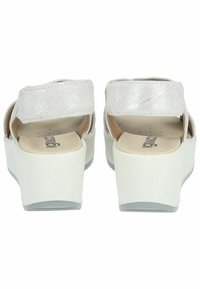 Sandali platform bianchi con una cinghia metallica testurizzata, apertura sul retro e soletta imbottita. La suola è liscia e leggermente curvata.
