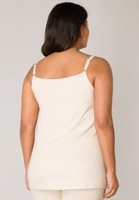 Beige tanktop met brede bandjes, met een rechte halslijn en zachte katoenen stof. Details zijn verstelbare bandhardware.