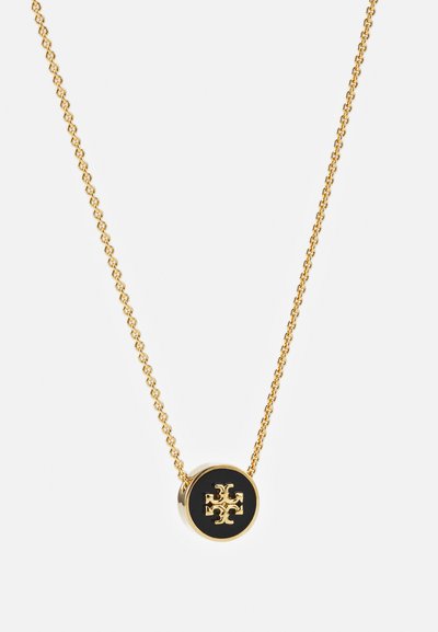 Colar de corrente de ouro com um pendente circular com fundo preto e um design de logótipo em relevo, destacando uma textura suave.