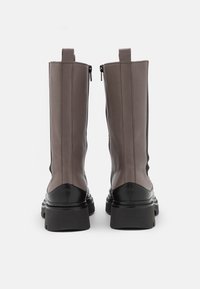 Botas de cuero marrón hasta el tobillo con suelas de goma negra, que presentan un acabado suave, punteras redondeadas y cremalleras laterales para un fácil calzado.