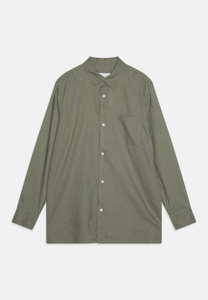 Hosszú ujjú, gombos ing olívazöld szövetből. Jellemzője a hegyes gallér, egyetlen mellzseb és fehér gombok az elején.