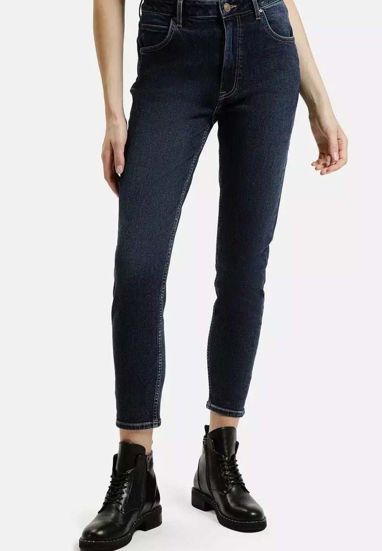 Ciemnoniebieskie spodnie skinny z wysokim stanem, pięcioma kieszeniami i kontrastowym przeszyciem, zestawione z czarnymi sznurowanymi botkami za kostkę.