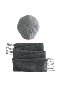 Szara wełniana czapka z ośmioma panelami i guzikiem na górze, w połączeniu z długim szarym szalikiem z frędzlami. Miękka tekstura, jednolity kolor.