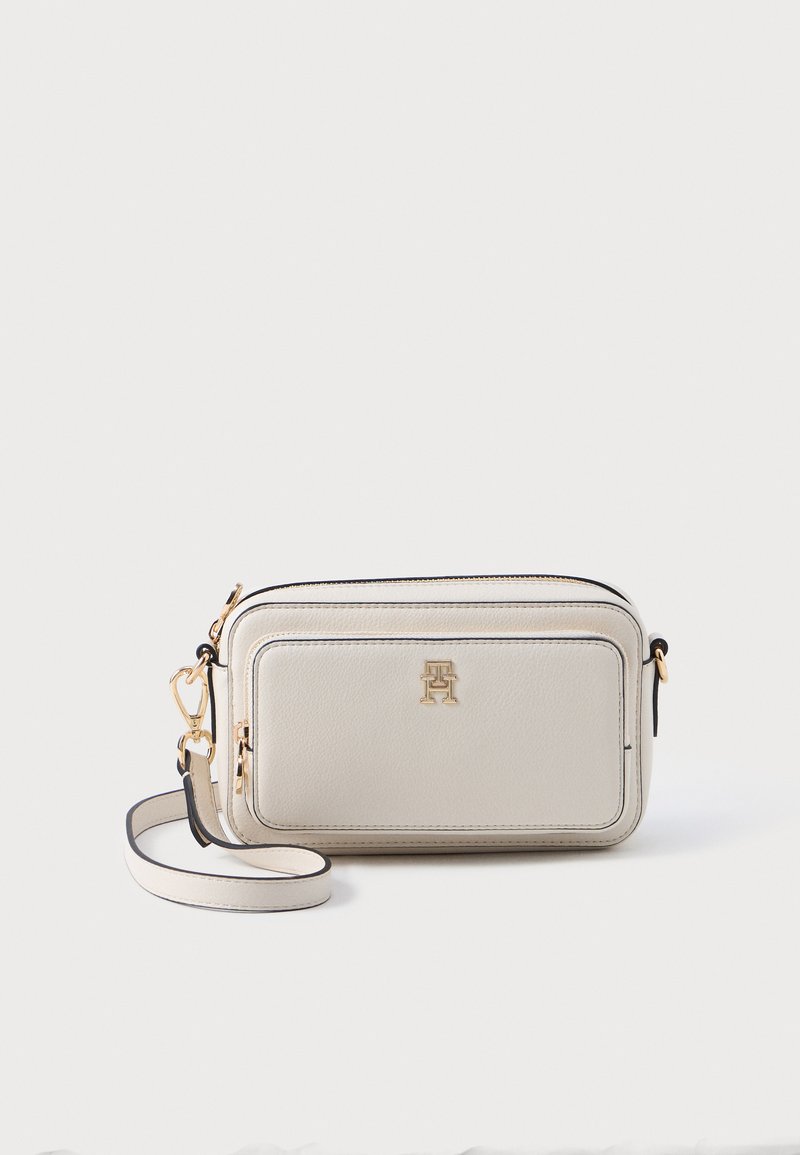 Beige leren schoudertas met gouden hardware, zwarte accenten, een voorkantzak en een verstelbare strap. Rechthoekige vorm en gestructureerde afwerking.