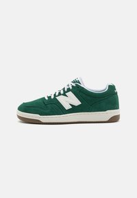 Green suede sneakers with white accents, round laces, and a gum sole. Features a prominent white "N" logo on the side. Low-top design.
