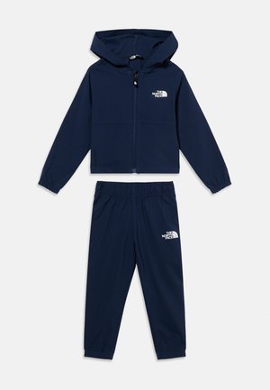 Tengerészkék gyerek kapucnis pulóver és rugalmas derékpántos nadrág szett, elülső cipzárral és The North Face logókkal a mellkason és a combon.
