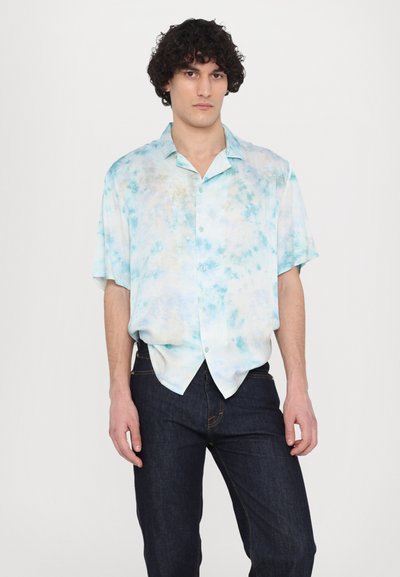 Kortærmet skjorte med knap i lyseblå farve med tie-dye mønster; blødt stof; båret med mørke denim jeans; krave-design.