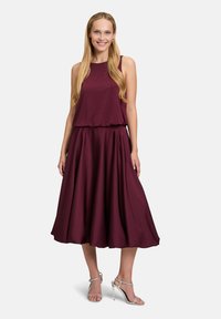 Abito bordeaux con top senza maniche e gonna fluida. Realizzato in tessuto liscio, presenta un design a strati con accenti di un sottile motivo a punti.