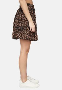 Leopardprint rok met een geplooide zoom, gemaakt van zachte stof. Beschikt over een elastische tailleband en een relaxed A-lijn vorm; gedragen met witte sneakers.