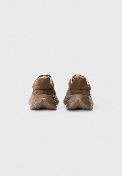Bruna mockasinsneakers med en tjock, texturerad sula, som har en flexibel design och subtil logotyp på baksidan.