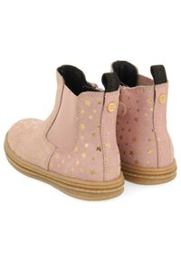 Stivali alla caviglia in suede rosa con motivo a stelle dorate, pannelli laterali elastici, suole in gomma marrone e dettagli metallici dorati sul retro.