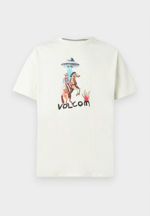 Jasnobeżowa bawełniana koszulka z grafiką kowboja jeźdźca na koniu pod UFO, z napisem „VOLCOM” w czerni.