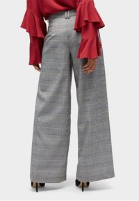 Pantalons à jambes larges en tartan gris et noir, présentant une taille haute et une texture de tissu lisse.
