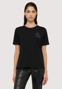 Czarna bawełniana koszulka z krótkim rękawem i okrągłym dekoltem, z niebieskim graficznym logo na lewej stronie klatki piersiowej. Gładka struktura.