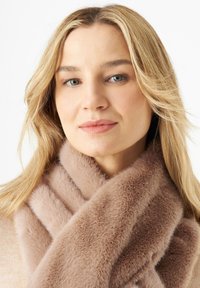 Écharpe en fausse fourrure beige clair, présentant une texture douce et moelleuse ainsi qu'un design large, enroulée autour du cou.