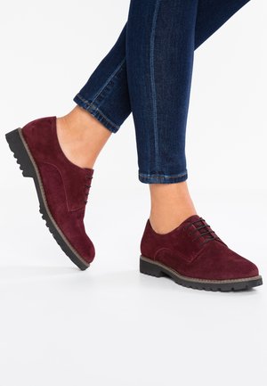 Bordeaux ruskind snørebåndssko med rund tå, tekstureret overflade og gummisål med rillede detaljer for bedre greb.