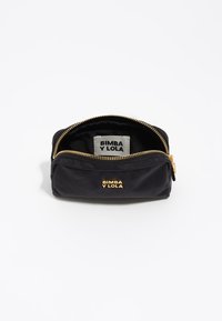 Neceser de tela negra con cremallera dorada y marca. Presenta una forma rectangular simple y una textura suave. Etiqueta visible en el interior.