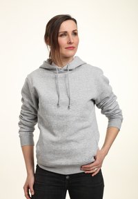 Felpa grigia in cotone con tasca frontale, cappuccio regolabile con cordino e polsini a coste, abbinata a pantaloni jeans scuri. Texture liscia, design casual.